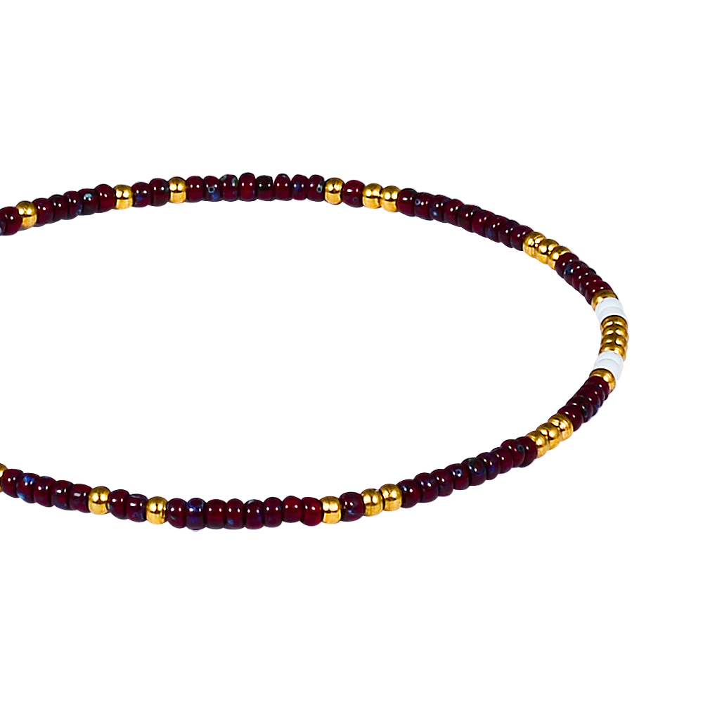 Beaded bracelet with red, gold, and white beads on a white background